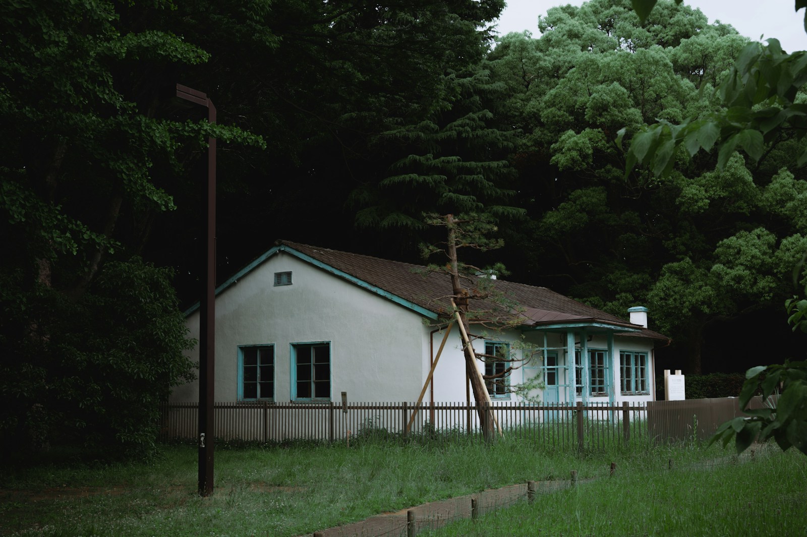 a white house with a fence and trees in the background