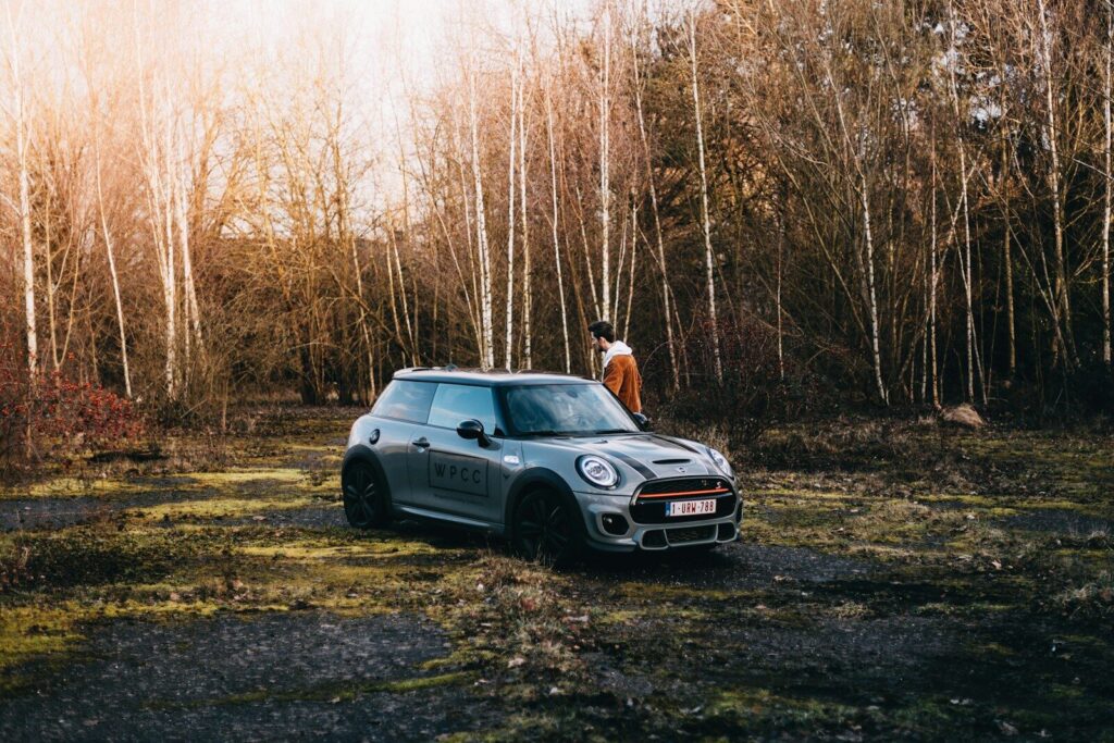 a man standing next to a car in a forest